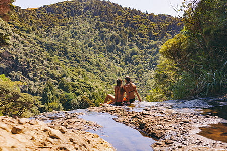 two women sitting on rock facing forest thumbnail