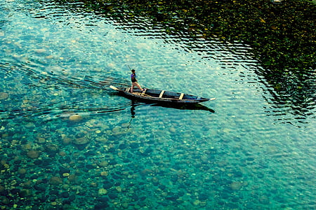 person standing on rowboat during daytime thumbnail