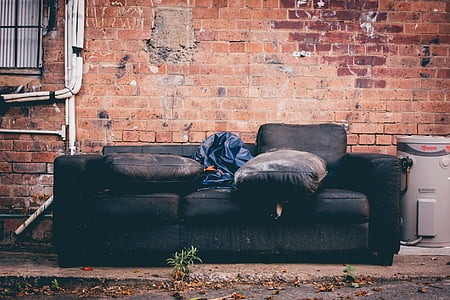 black 3-seat sofa beside brick wall thumbnail