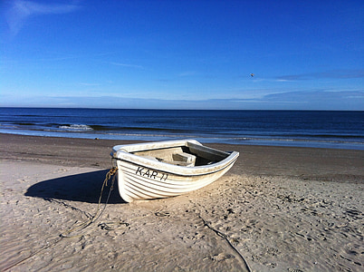 white canoe dock on brown sand near body of water at daytime thumbnail