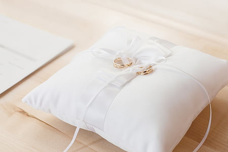 two gold-colored wedding rings on white pillow thumbnail