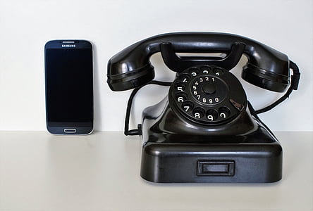 black rotary dial telephone and black Samsung Galaxy Android smartphone on white surface thumbnail
