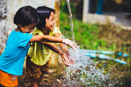 two girls playing water while standing during daytime thumbnail