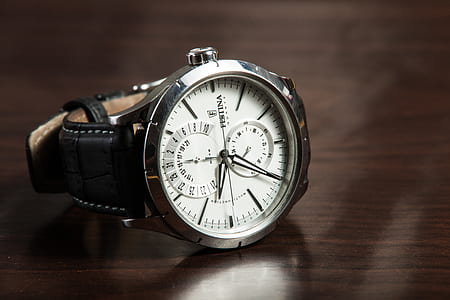 round silver-colored framed chronograph watch with black leather strap on brown wooden surface thumbnail