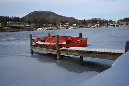 A canoe on a snowy dock by a lake. thumbnail