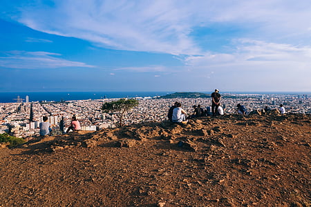 group of people sitting on mountain top overlooking city thumbnail