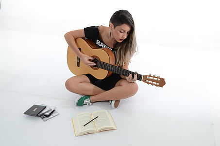 woman playing guitar inside white painted room thumbnail