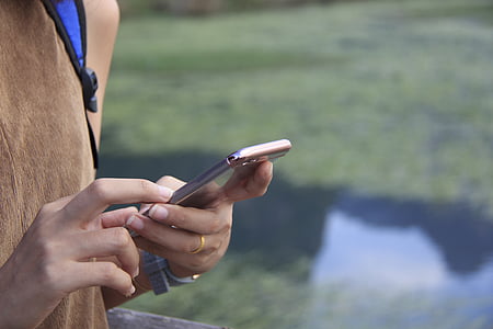person using cellphone near body of water thumbnail