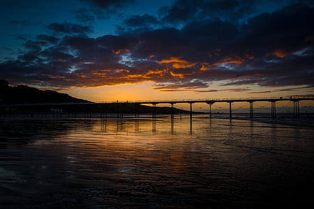 gray bridge on calm water under black and gray sky thumbnail