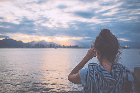 woman wearing blue dress in front of body of water thumbnail