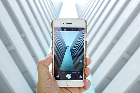 A photographer takes a photo of a building with his iPhone mobile smartphone camera thumbnail