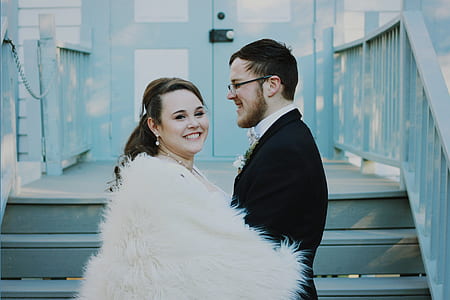 bride and groom standing on blue wooden stairs near blue wooden doors thumbnail