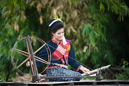 shallow focus photography of woman using saxony wheel surrounded by trees thumbnail