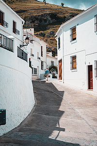 man walking between concrete building during daytime thumbnail