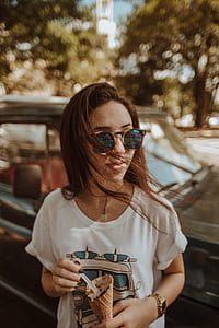 woman holding sugar cone and spoon beside black car at daytime thumbnail