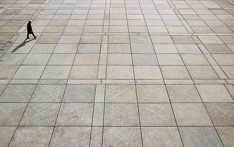 silhouette of person walking on gray concrete pavement high-angle photo thumbnail