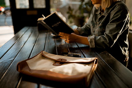person sitting on chair in front of table while reading book thumbnail