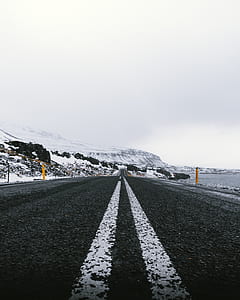 photo of black and white asphalt road near body of water thumbnail