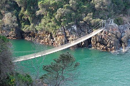 brown wooden bridge connecting gray stony islands thumbnail