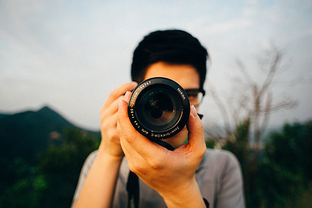 shallow focus photography of man holding DSLR camera thumbnail