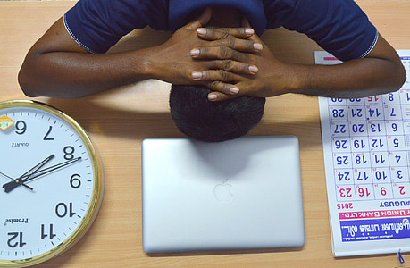 man lying on beige table near silver MacBook and brass-colored analog clock and monthly calendar thumbnail