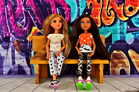 two girl dolls sitting on brown bench thumbnail