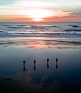 four person standing on shoreline during golden hour thumbnail