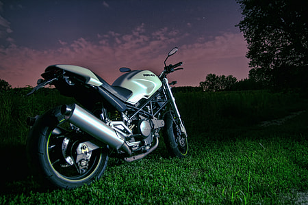 gray backbone motorcycle on green grass near trees at night thumbnail