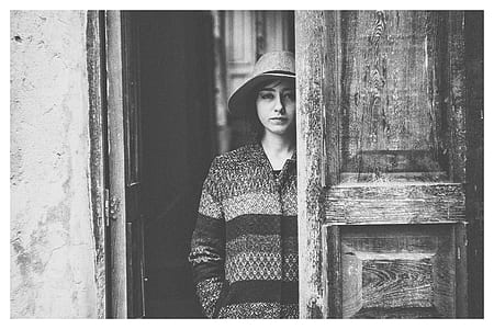 grayscale photo of a woman standing near door thumbnail