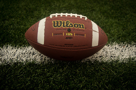 brown and white Wilson football on grass field thumbnail