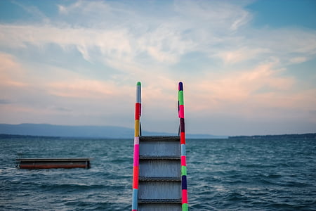 gray and multicolored ladder on body of water thumbnail