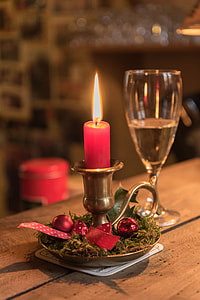 brass candle holder with red candle on top of brown wooden table thumbnail