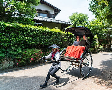 man pulling carriage with women riding on it thumbnail