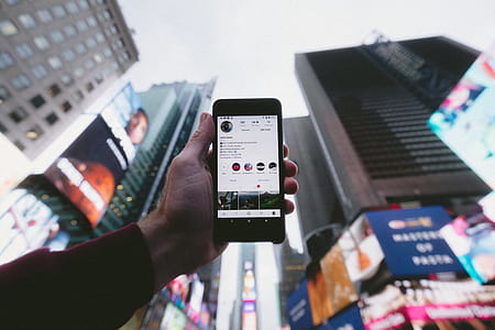 person holding smartphone showing instagram post thumbnail