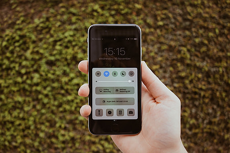 person holding space gray iPhone 6 Plus showing lock screen brightness thumbnail