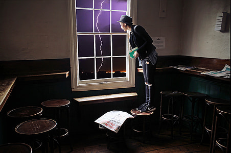 woman standing on brown wooden stool near white wooden window with lightning outside thumbnail