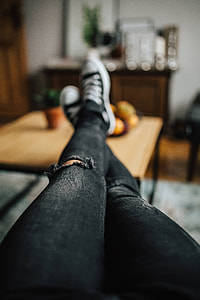 Woman in ripped jeans and black sneakers with a silver laptop on a wooden table thumbnail