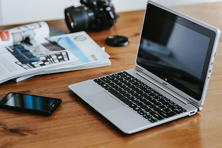 Silver laptop with various items on a table thumbnail