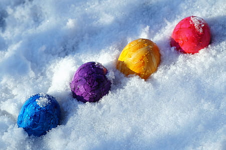 four assorted-color eggs on snow ground thumbnail