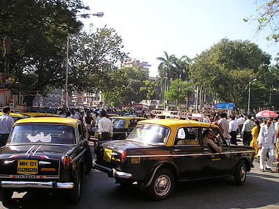 black and yellow sedan near group of people during daytime thumbnail