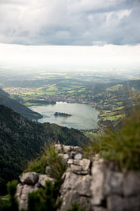 aerial photo of body of water surrounded with mountain under cloudy sky thumbnail