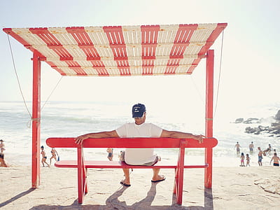 man sitting on bench facing seashore thumbnail