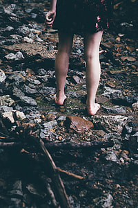 Woman in black and pink floral dress standing on rocky surface thumbnail