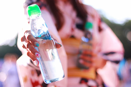 selective focus photography of woman holding clear glass water bottle thumbnail