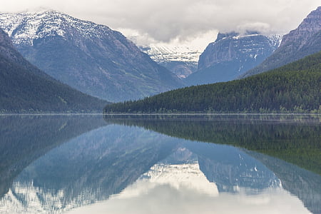 calm body of water near trees and mountains thumbnail