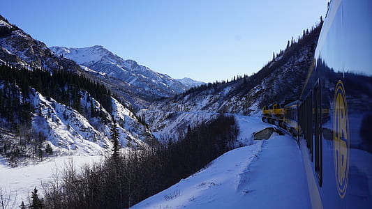 photograph of train passing beside mountain ranges thumbnail