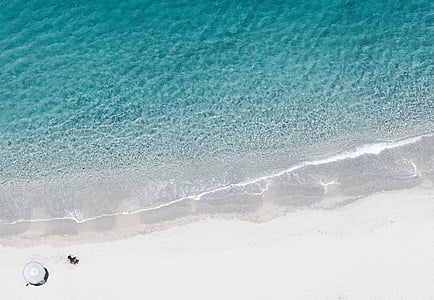 aerial photography of person on shore near umbrella thumbnail