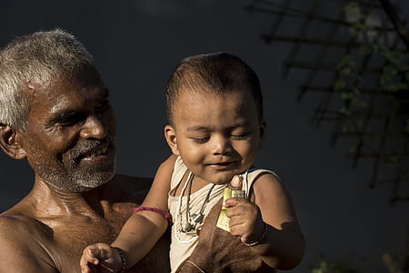 man holding baby wearing white tank top during daytime thumbnail