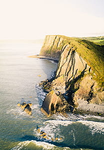 gray mountain surrounded ocean water under gray sky thumbnail