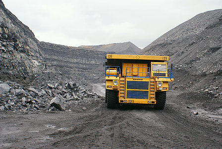 yellow heavy equipment in between gray mountains at daytime thumbnail